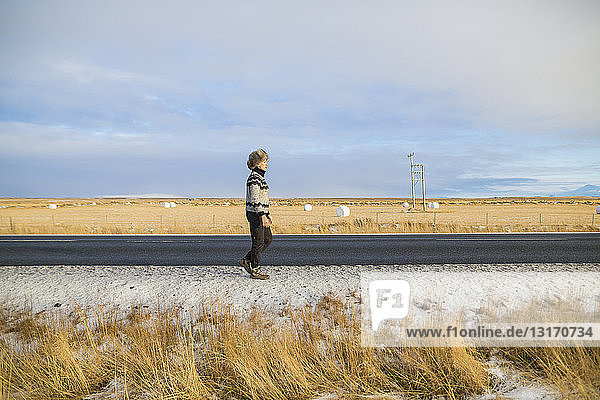 Frau zu Fuß entlang der Landstraße  Island