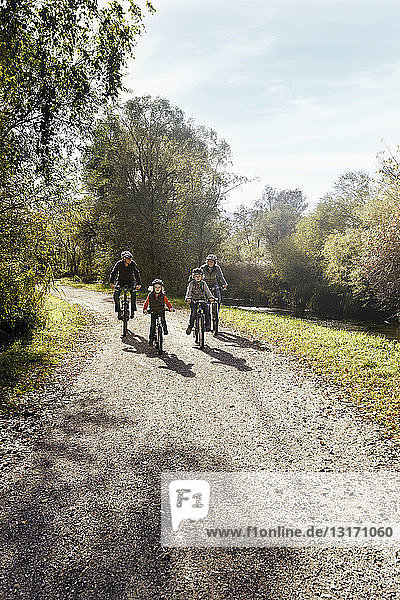 Front view of family on rural road riding bicycles
