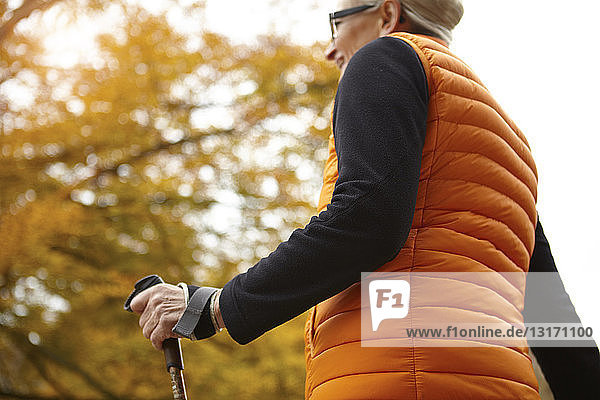 Low angle view of senior female nordic walker in autumn park