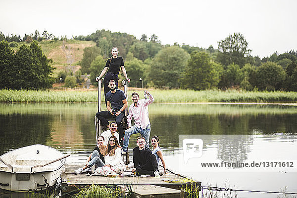Porträt glücklicher männlicher und weiblicher Freunde auf dem Steg über dem See während eines Wochenendausflugs