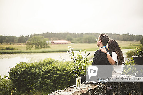 Ehepaar schaut auf den See,  während es auf einer Stützmauer sitzt