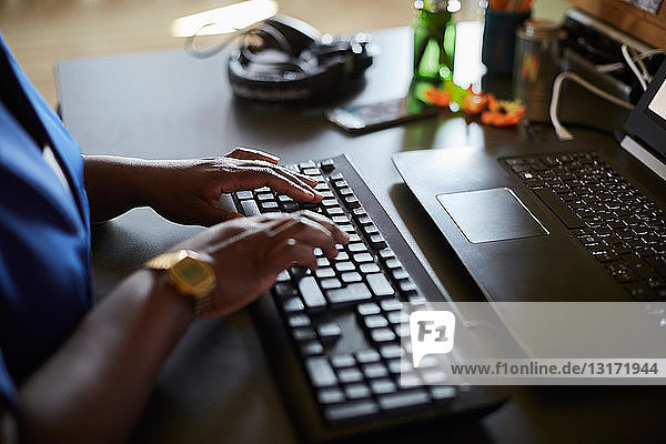 Midsection of businesswoman typing on keyboard at desk in creative office