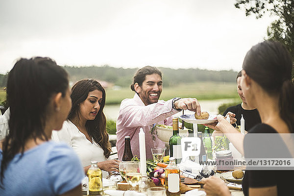 Männliche und weibliche Freunde genießen das Abendessen während einer Party im Hinterhof