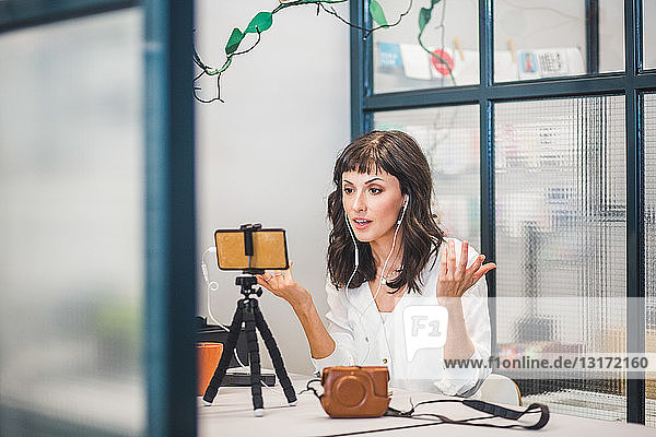 Kreative Geschäftsfrau nimmt an Videokonferenz über Mobiltelefon am Schreibtisch im Büro teil