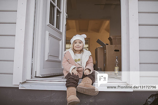 Young girl sitting in entrance  cardboard box