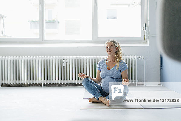 Schwangere Frau  die auf dem Boden sitzt und Yoga praktiziert