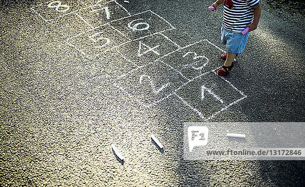 Kleines Mädchen mit gezeichneten Hüpfspiel auf der Straße  Teilansicht