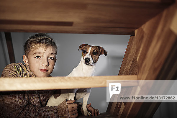 Porträt eines Jungen mit Jack Russel Terrier auf der Treppe zu Hause