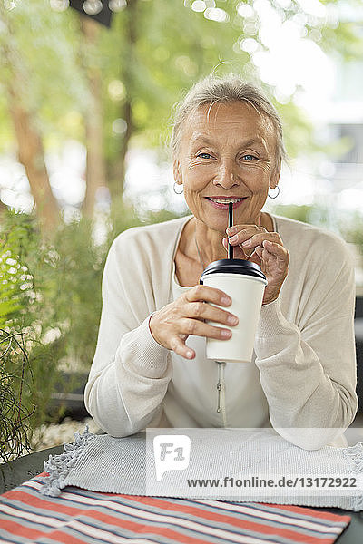 Porträt einer lächelnden älteren Frau in einem Straßencafé