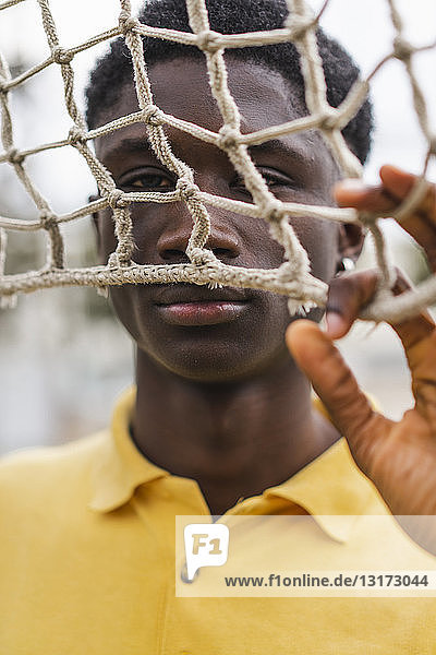 Junger schwarzer Mann schaut durchs Volleyballnetz