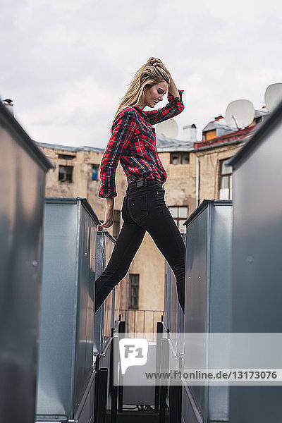 Modische junge Frau auf dem Dach in kariertem Hemd und schwarzer Jeans
