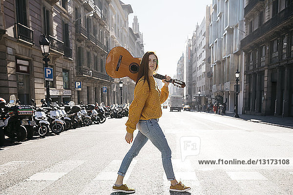 Red-haired woman with a guitar on zebra crossing