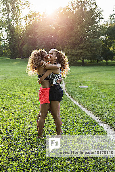 Zwillingsschwestern umarmen sich in einem Park