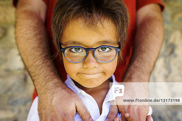 Portrait of little boy wearing glasses standing in front of his father
