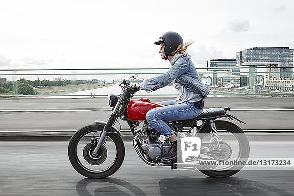 Deutschland  Köln  junge Frau mit Motorrad auf der Brücke
