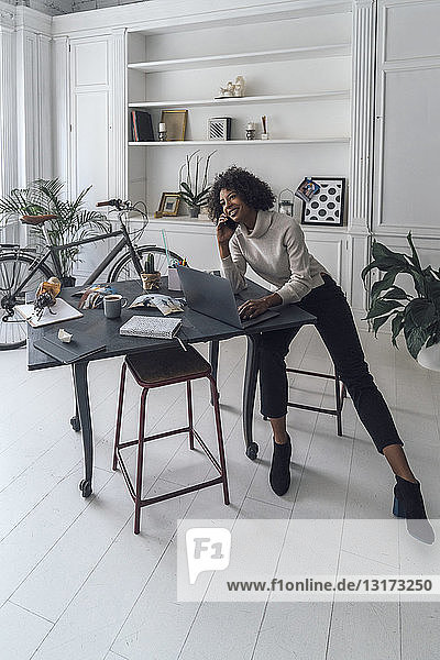 Mittlere erwachsene Frau  die in ihrem Heimbüro arbeitet und einen Laptop benutzt