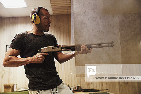 Mann schießt mit einem Gewehr in einem Schießstand