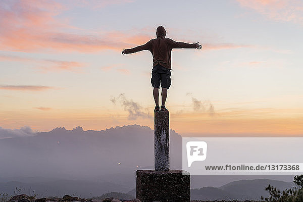 Spain  Barcelona  Natural Park of Sant Llorenc  man standing on pole at sunset