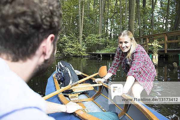Glückliches junges Paar beim Einsteigen ins Kanu in einem Waldbach