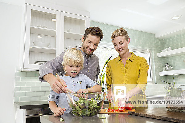 Lächelnde Familie bereitet gemeinsam Salat in der Küche zu