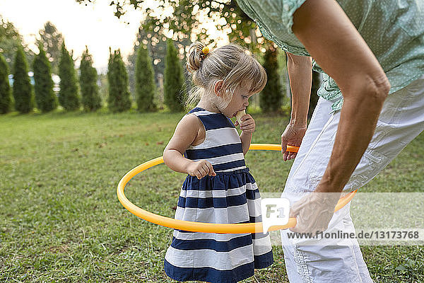 Grandmother and granddaughter playing together in garden with hoola hoop