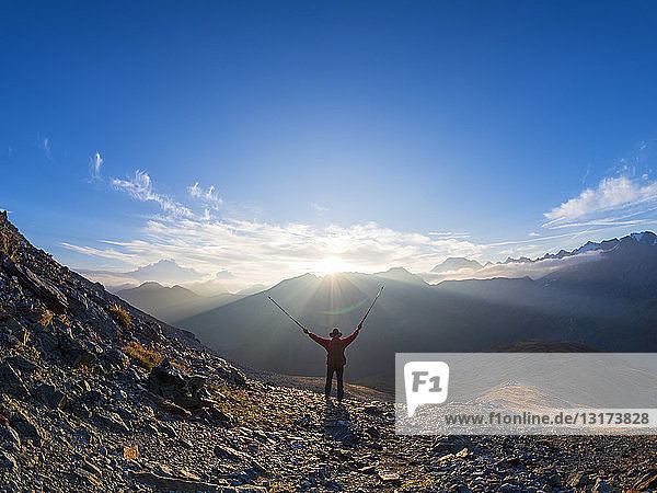 Border region Italy Switzerland  cheering senior man with hiking poles in mountain landscape at Piz Umbrail