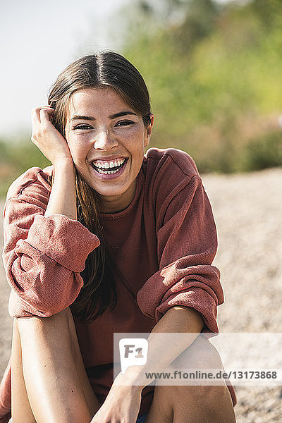 Porträt einer lachenden jungen Frau  die im Freien sitzt