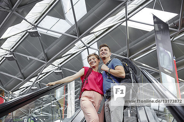 Glückliches Paar auf der Rolltreppe am Flughafen