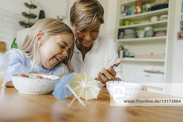 Happy mother and daughter having fun at table at home