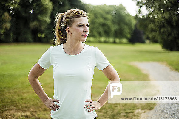 Sportive young woman standing in a park looking sideways