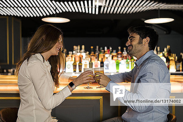 Lächelndes Paar klimpert auf Biergläser in einer Bar