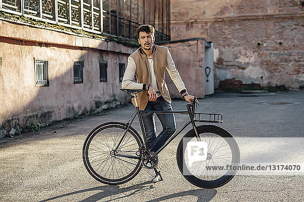 Junger Mann mit Pendler-Fixie-Fahrrad auf einem Hinterhof in der Stadt