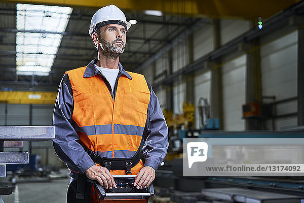 Portrait of man in factory operating machinery with remote console