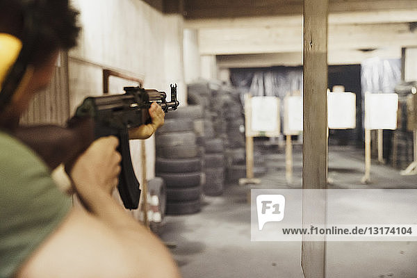 Man aiming with a rifle in an indoor shooting range