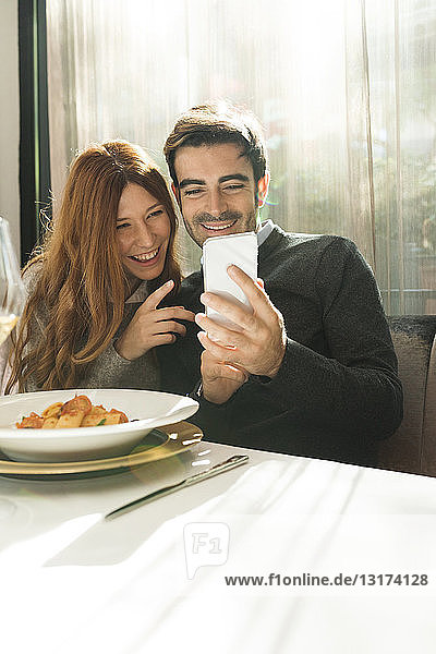 Happy couple looking at cell phone in a restaurant