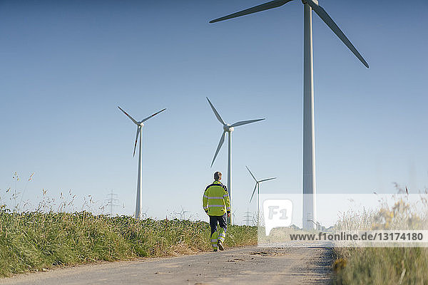 Ingenieur zu Fuß auf einem Feldweg bei einem Windpark