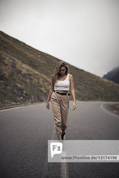 Blonde woman walking on a road blurry person