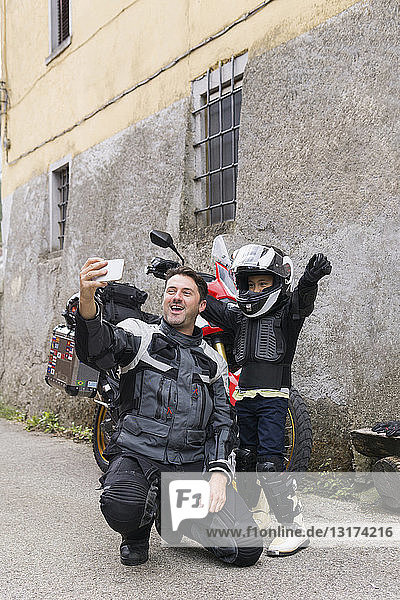 Happy father and son taking a selfie on a motorbike trip