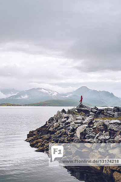 Norwegen  Senja  Mann steht auf Fels an der Küste