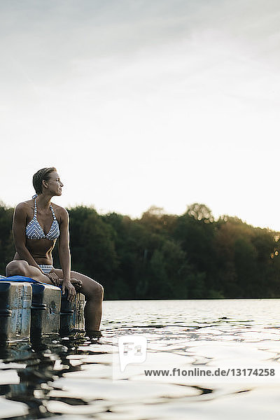 Frau im Bikini  die auf einem Schwimmer auf einem See sitzt