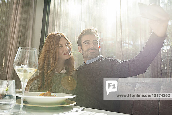 Smiling couple taking a selfie in a restaurant