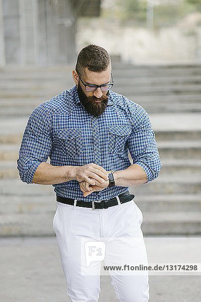 Bearded hipster businessman checking the time