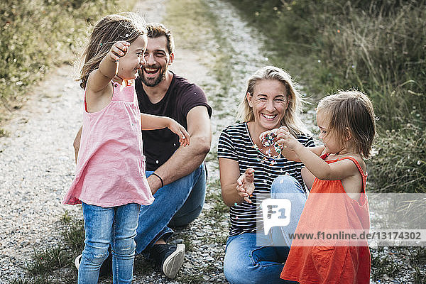 Glückliche Familie mit zwei Töchtern  die auf einem Feldweg mit Konfetti spielen