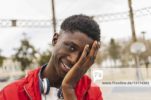 Porträt eines jungen schwarzen Mannes  lachend mit der Hand im Gesicht
