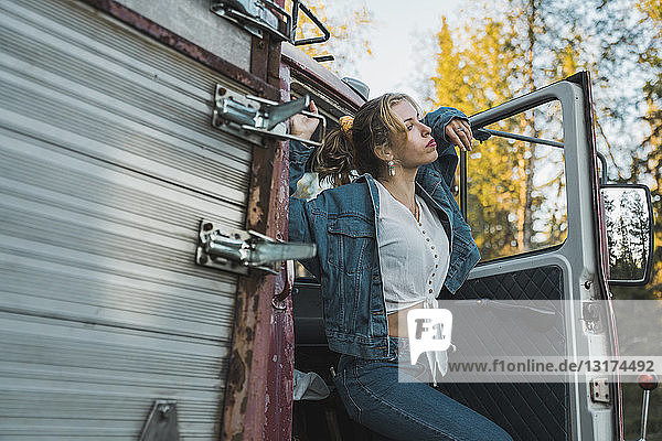 Young woman posing on broken vintage truck