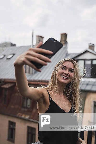Porträt einer lächelnden blonden Frau  die auf der Dachterrasse Selbsthilfe betreibt