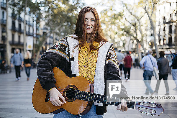 Rothaarige Frau spielt Gitarre in der Stadt