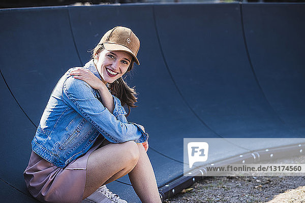 Porträt einer lächelnden jungen Frau  die im Freien sitzt
