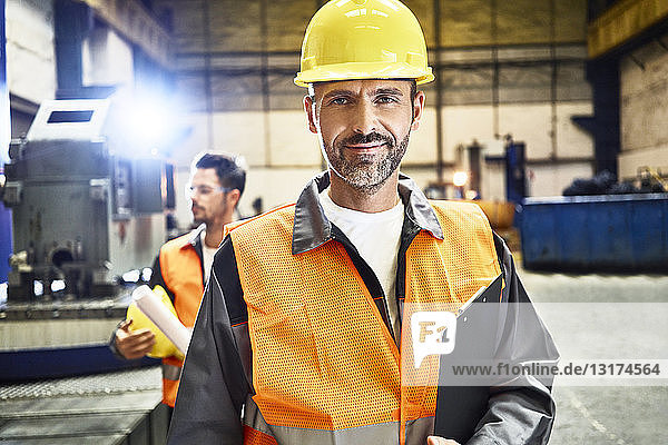 Portrait of smiling man wearing protective workwear in factory