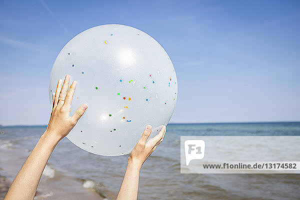 Hands of a girl holding a balloon at the beach